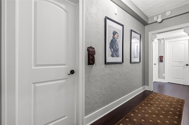 corridor featuring dark wood-type flooring and a textured ceiling