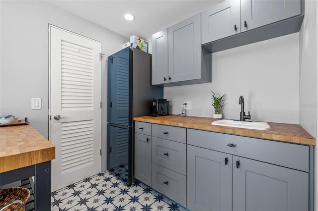 kitchen with gray cabinetry, sink, and butcher block counters