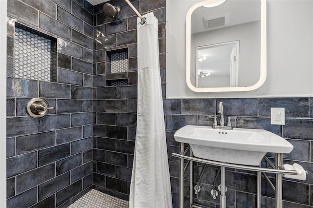 bathroom featuring a shower with shower curtain, tile walls, and sink