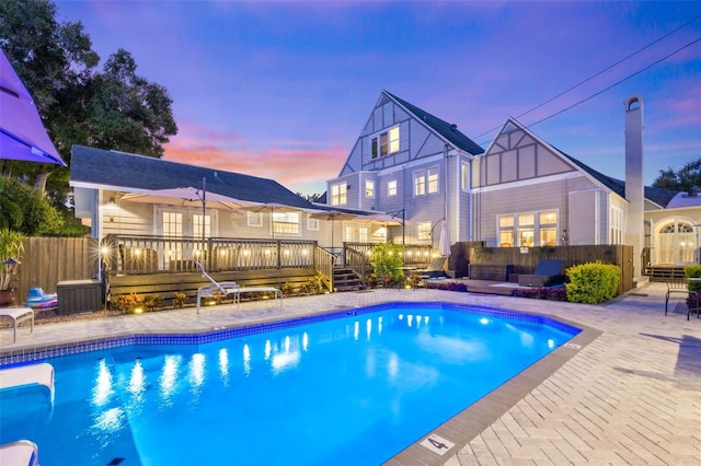 pool at dusk featuring a patio area and a deck