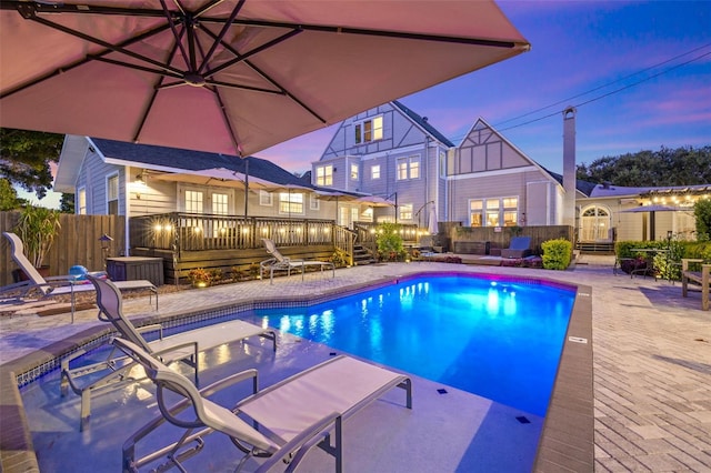 pool at dusk with a patio and a deck