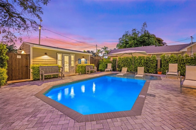 pool at dusk with a patio area