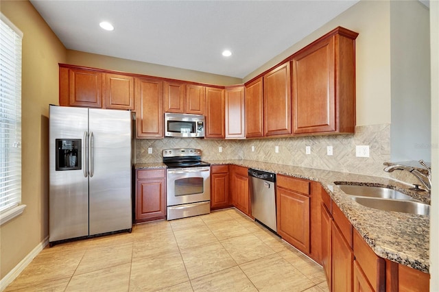 kitchen with light stone countertops, appliances with stainless steel finishes, light tile patterned floors, and sink