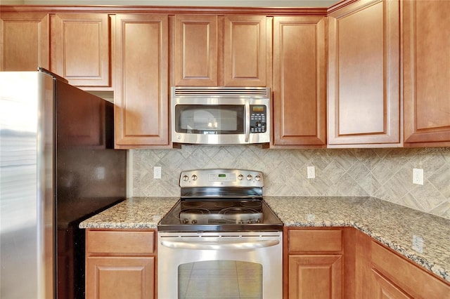 kitchen featuring backsplash, light stone counters, and stainless steel appliances