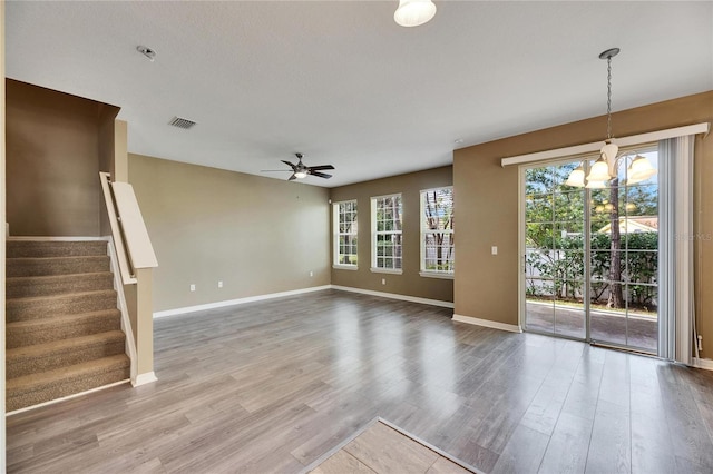 unfurnished living room featuring hardwood / wood-style floors and ceiling fan with notable chandelier