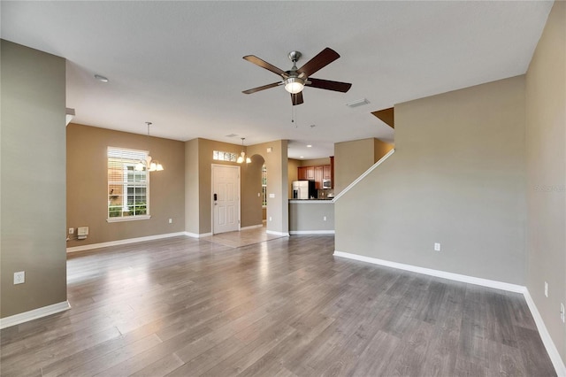 unfurnished living room featuring wood-type flooring and ceiling fan with notable chandelier