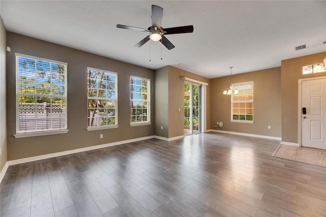 spare room with dark hardwood / wood-style flooring and ceiling fan with notable chandelier