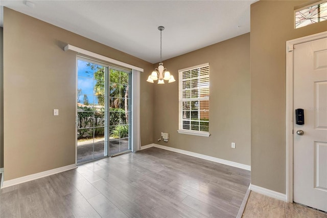 unfurnished dining area featuring a chandelier and wood-type flooring