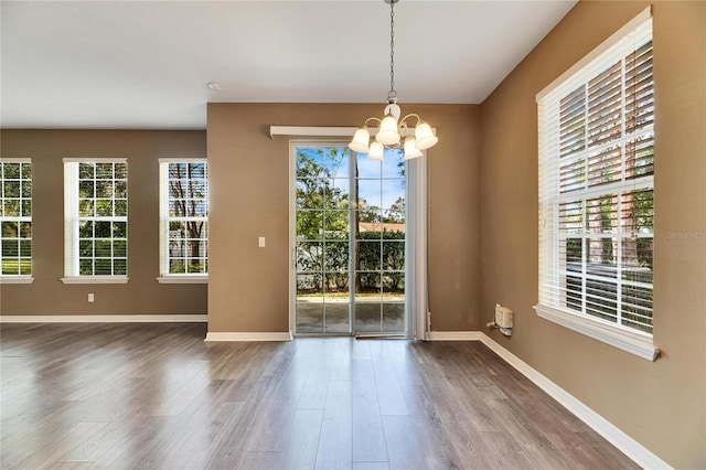 unfurnished dining area featuring a chandelier and hardwood / wood-style flooring