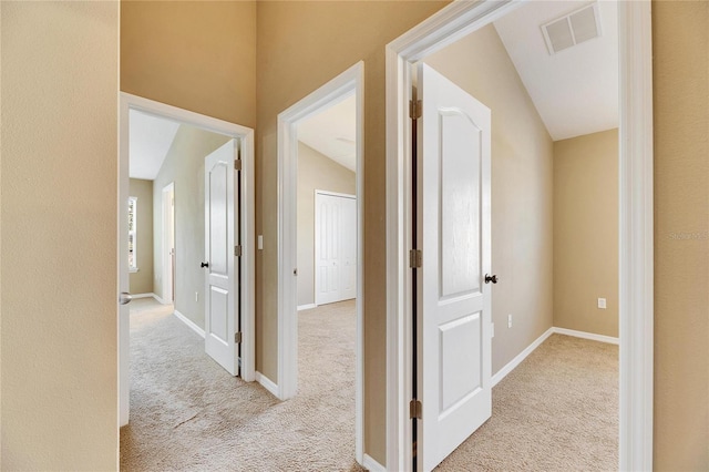 hall featuring light carpet and vaulted ceiling