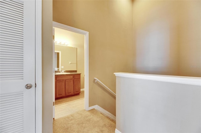 hallway featuring sink and light colored carpet