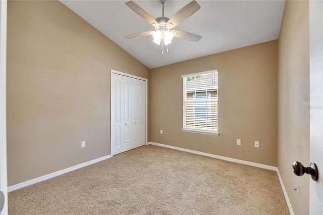 unfurnished bedroom featuring ceiling fan, light colored carpet, lofted ceiling, and a closet