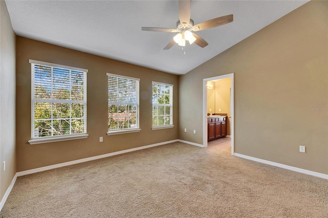 unfurnished room featuring light carpet, plenty of natural light, ceiling fan, and vaulted ceiling