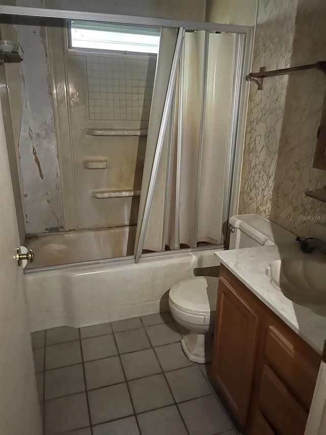 full bathroom featuring combined bath / shower with glass door, vanity, tile patterned floors, and toilet