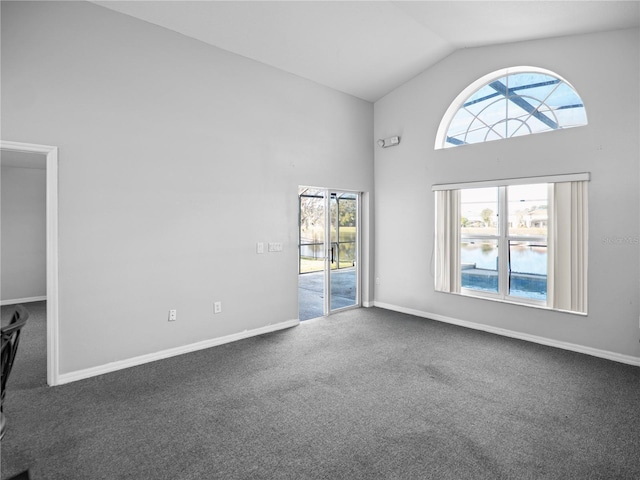 spare room featuring dark colored carpet, a water view, and high vaulted ceiling