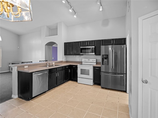 kitchen featuring sink, light tile patterned floors, stainless steel appliances, and decorative light fixtures