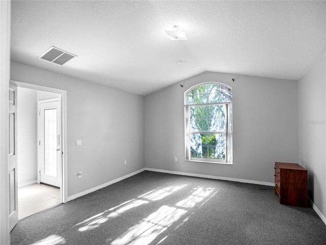 carpeted empty room with a textured ceiling and vaulted ceiling