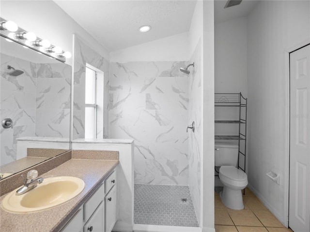 bathroom with a tile shower, tile patterned flooring, lofted ceiling, toilet, and vanity