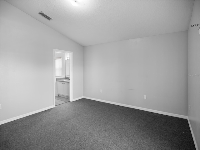 empty room featuring lofted ceiling, light carpet, and a textured ceiling