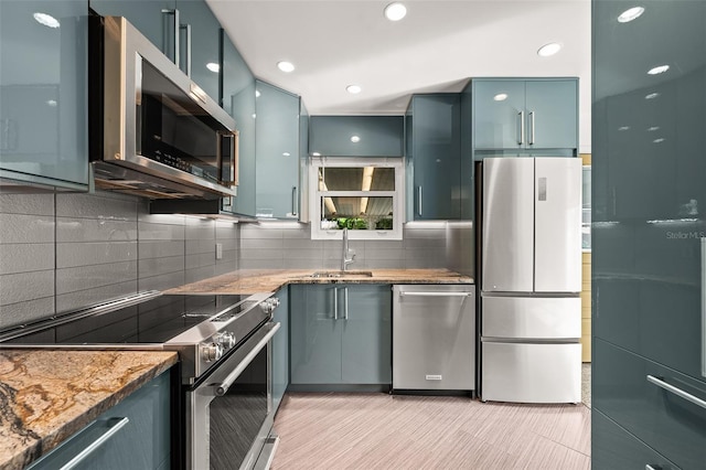 kitchen featuring light stone countertops, recessed lighting, a sink, decorative backsplash, and stainless steel appliances