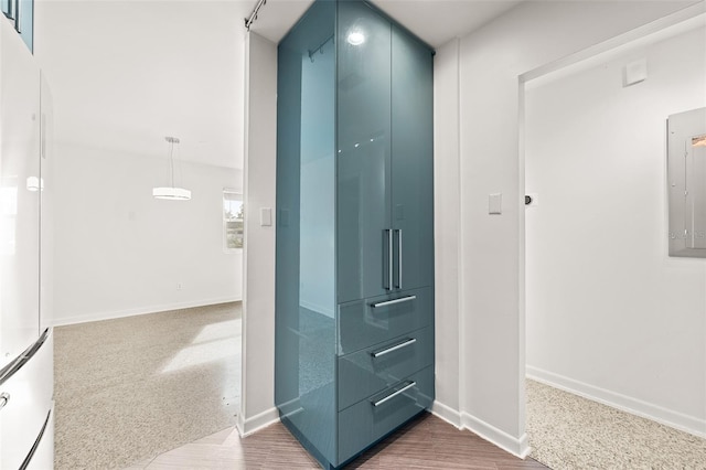 corridor with electric panel, wood finished floors, and baseboards