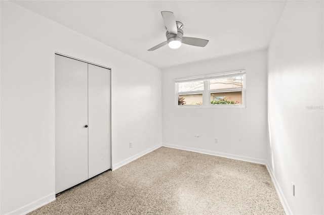 unfurnished bedroom featuring a closet, baseboards, ceiling fan, and speckled floor