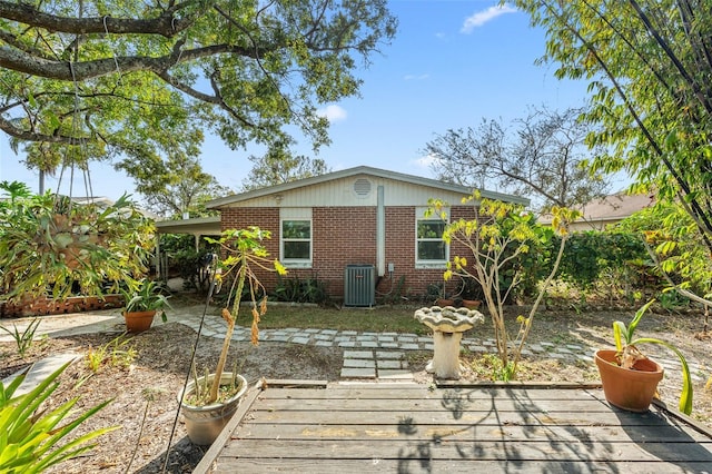 back of property with brick siding and central AC unit