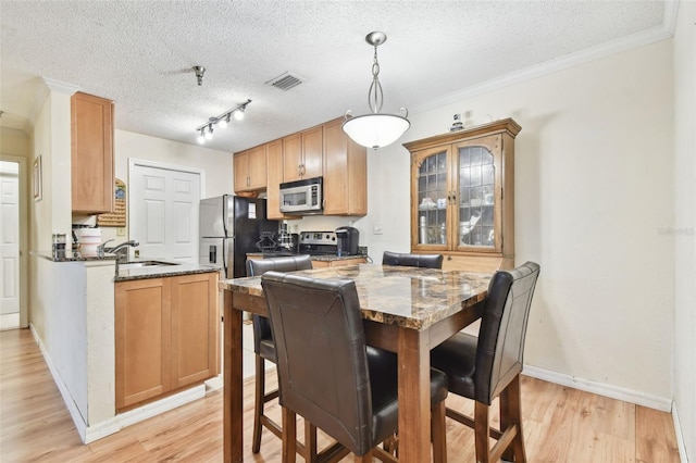 kitchen with sink, stainless steel refrigerator, a textured ceiling, and dark stone counters