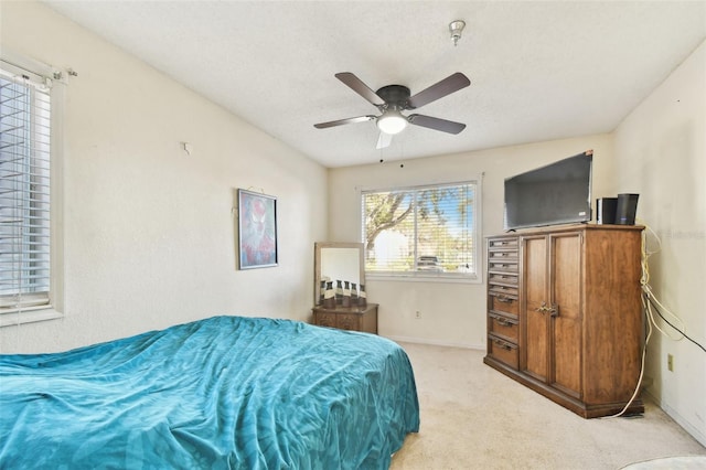 bedroom featuring a textured ceiling, light colored carpet, and ceiling fan