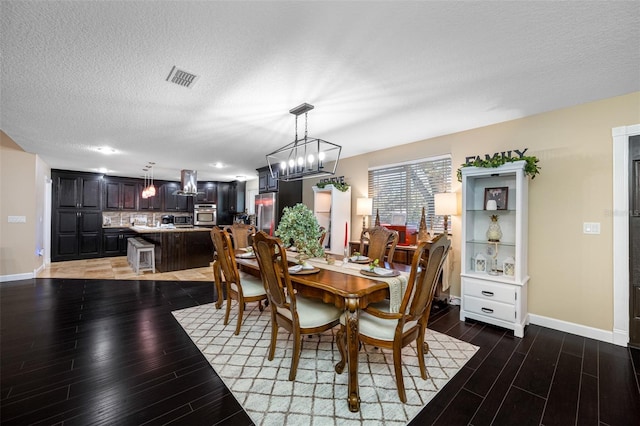 dining room featuring baseboards, a notable chandelier, visible vents, and light wood-type flooring