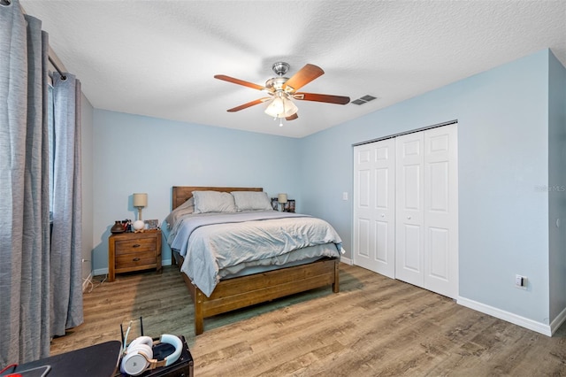 bedroom with visible vents, baseboards, wood finished floors, a closet, and ceiling fan