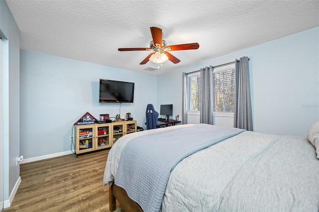 bedroom featuring baseboards, wood finished floors, a textured ceiling, and ceiling fan