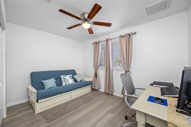home office with baseboards, a ceiling fan, light wood-style floors, and visible vents