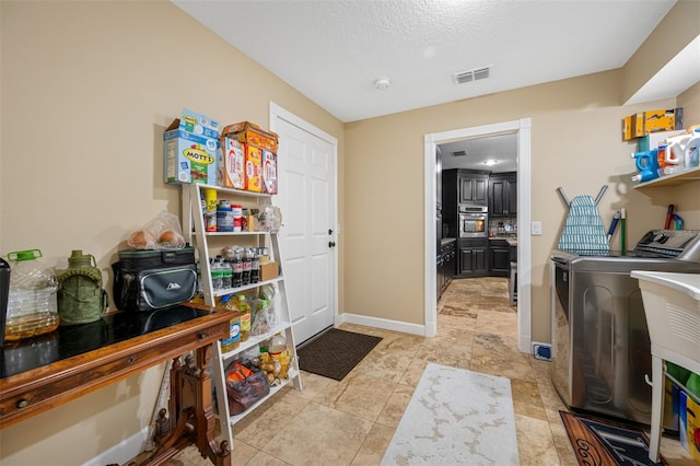 laundry area featuring washer and clothes dryer, a textured ceiling, visible vents, baseboards, and laundry area