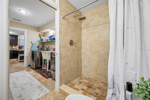 full bath with a textured ceiling, a shower stall, visible vents, and washer / clothes dryer