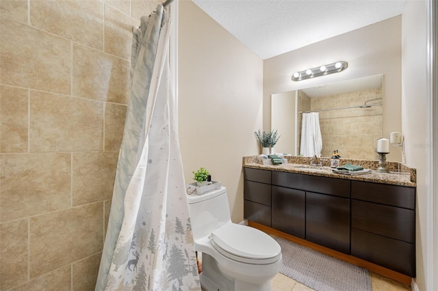 bathroom with tiled shower, vanity, tile patterned flooring, and toilet