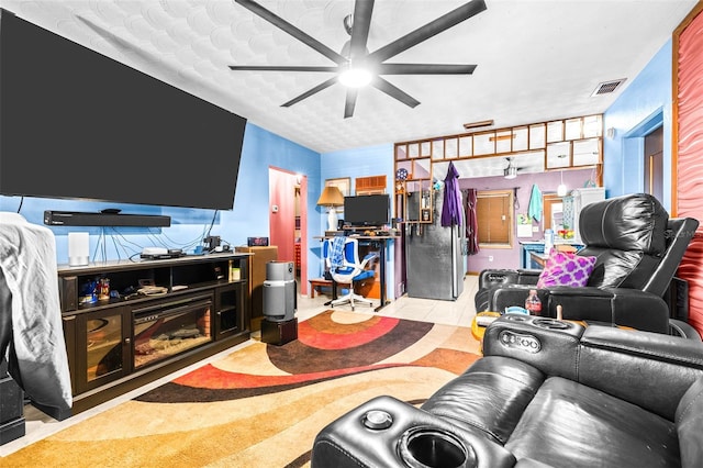 living room with ceiling fan and a textured ceiling