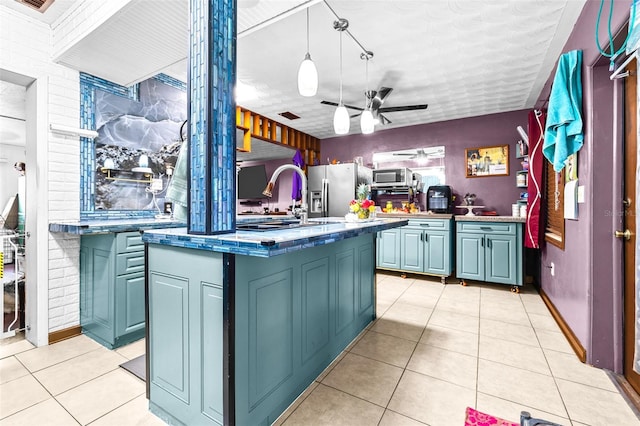 kitchen with ceiling fan, stainless steel appliances, pendant lighting, a kitchen island with sink, and light tile patterned floors