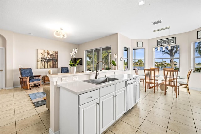 kitchen featuring dishwasher, a kitchen island with sink, sink, light tile patterned floors, and white cabinetry