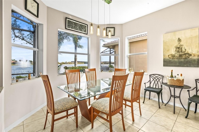 tiled dining room featuring plenty of natural light and a water view