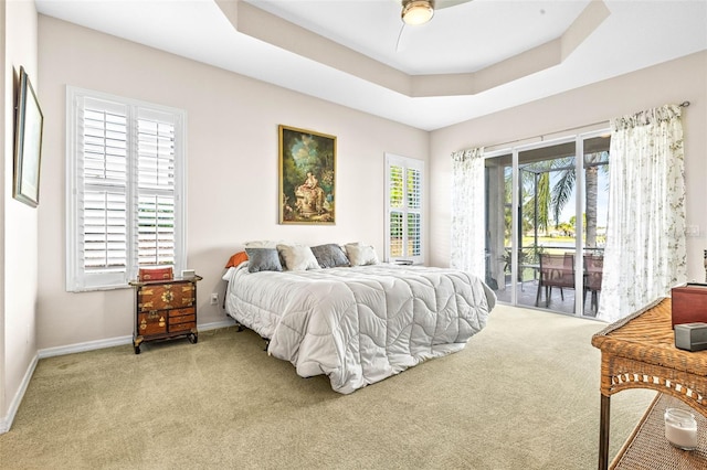 carpeted bedroom featuring access to outside, a raised ceiling, and ceiling fan