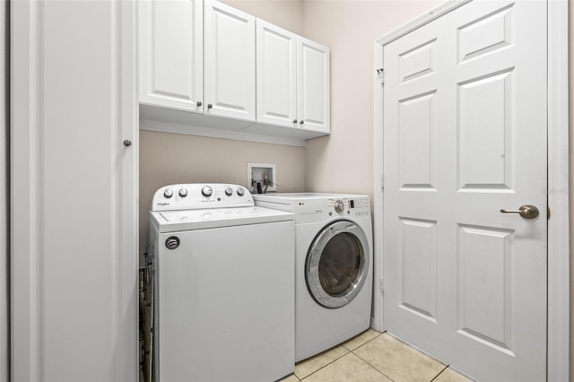 laundry room featuring washer and clothes dryer, light tile patterned floors, and cabinets