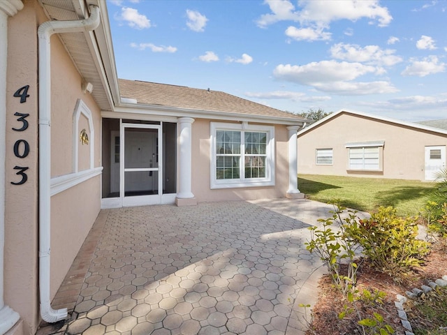 doorway to property featuring a patio and a lawn