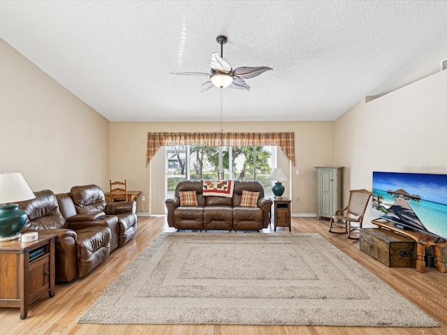 living room featuring ceiling fan, a textured ceiling, and light hardwood / wood-style flooring