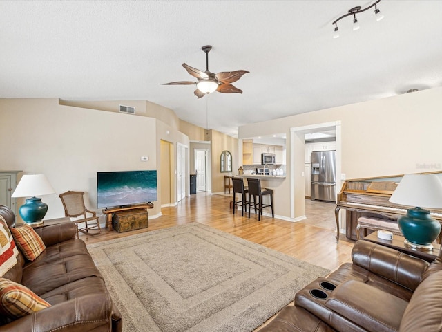 living room with light hardwood / wood-style floors, ceiling fan, and lofted ceiling