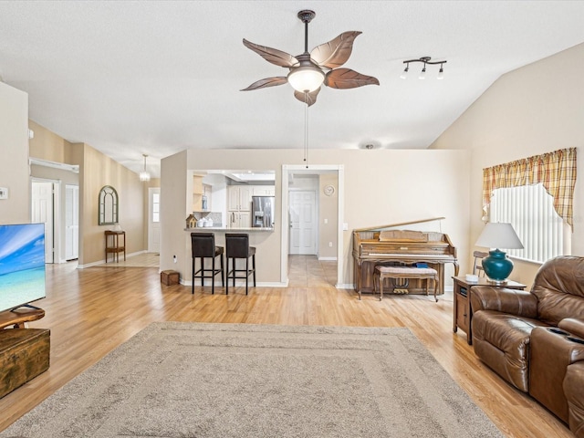 living room featuring a textured ceiling, ceiling fan, light hardwood / wood-style floors, and vaulted ceiling