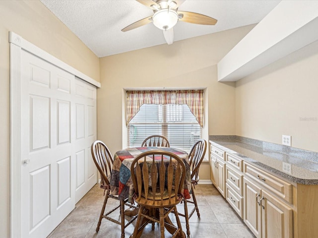 dining room with a textured ceiling, ceiling fan, light tile patterned floors, and vaulted ceiling