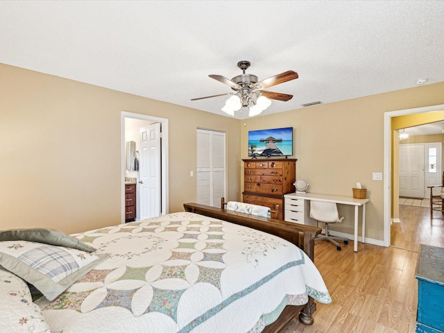 bedroom with ceiling fan, light hardwood / wood-style flooring, ensuite bathroom, and a textured ceiling