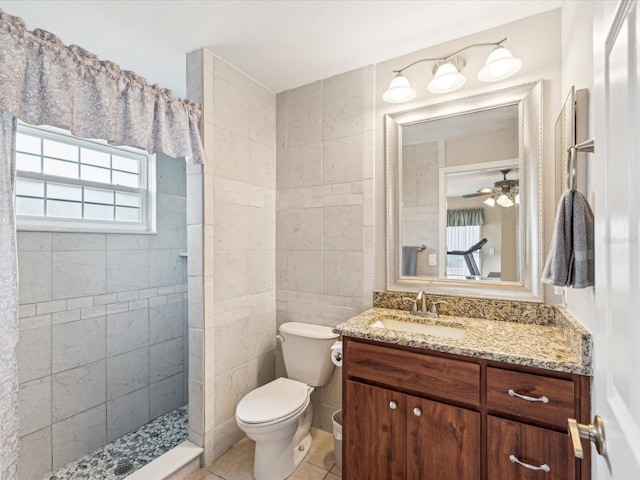 bathroom with vanity, tile patterned flooring, ceiling fan, toilet, and a tile shower