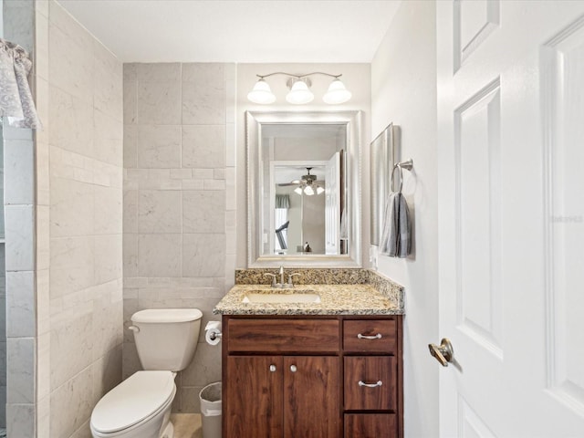 bathroom with vanity, ceiling fan, toilet, and tile walls